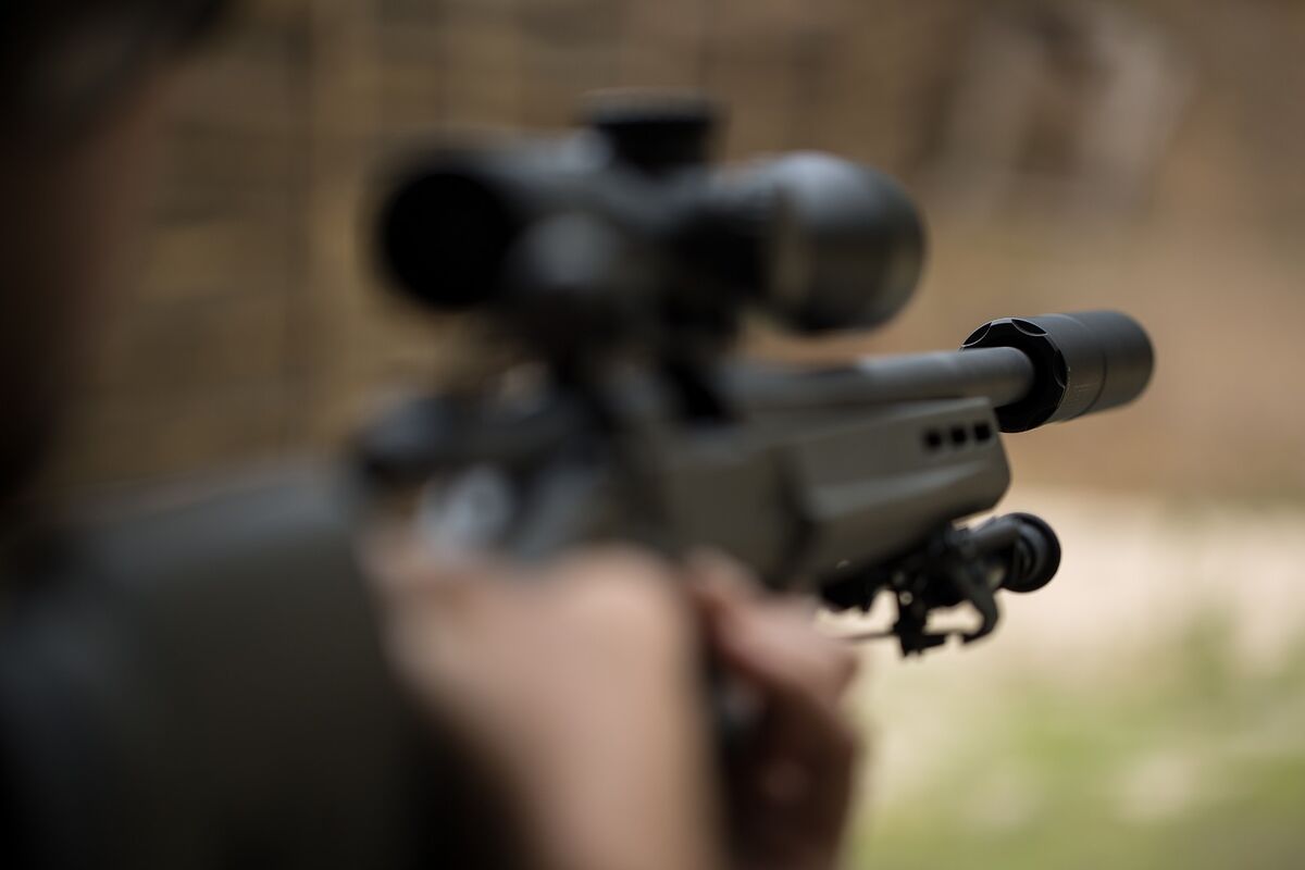 Waffe mit Zielfernrohr und Schalldämpfer im Anschlag
